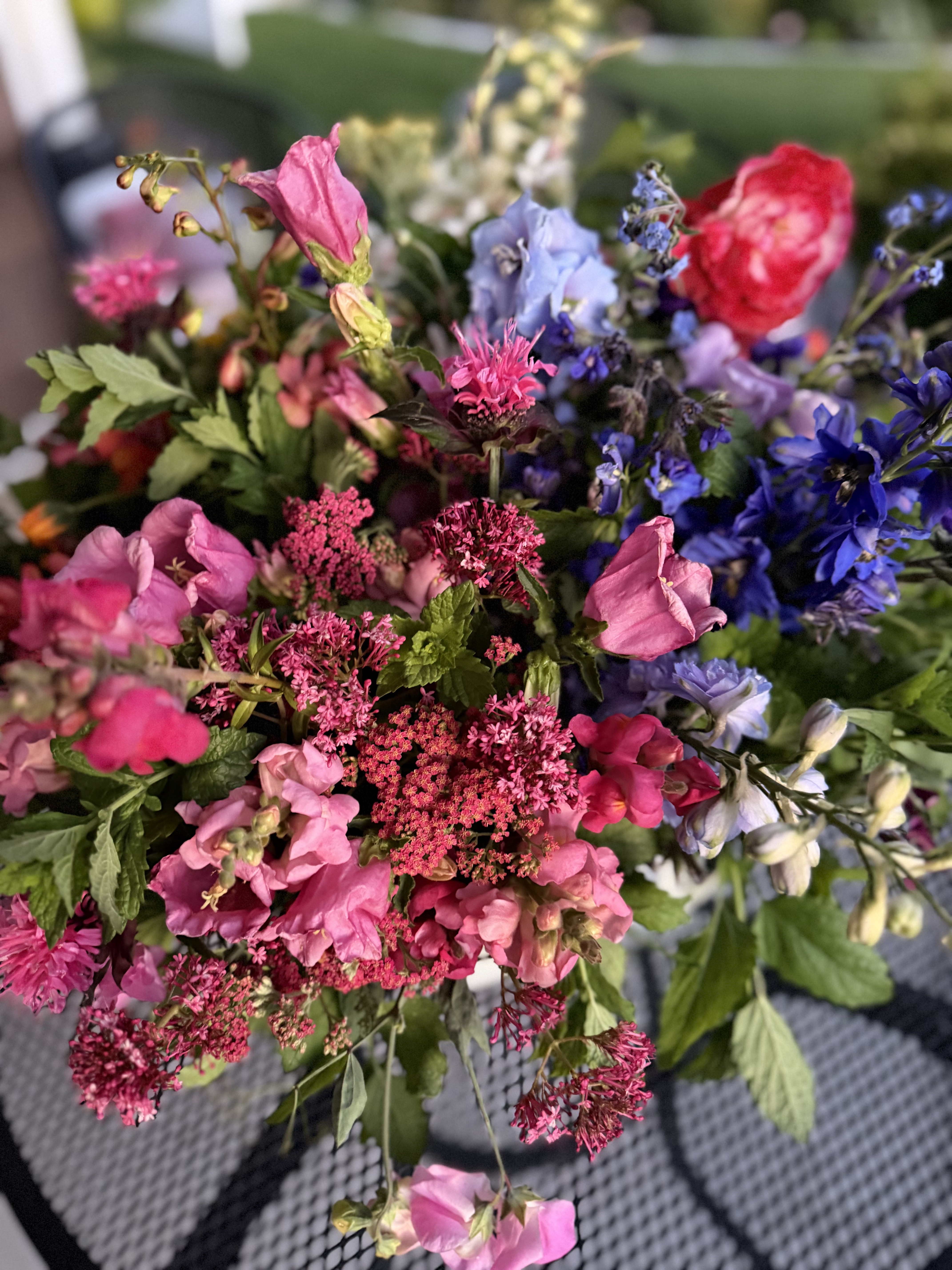 A hand-tied bouquet of pink dahlias, lavender, and powder blue delphinium against a cream linen backdrop.